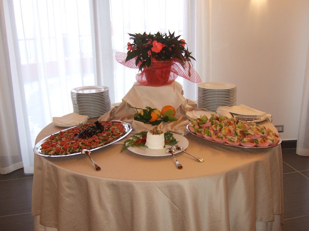 A buffet table with various dishes, a decorative plant, and stacked plates.