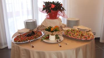 A buffet table with various dishes, a decorative plant, and stacked plates.