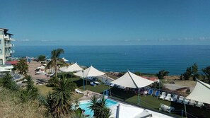 A resort with a pool, beach umbrellas, and a view of the sea. - Tus' Hotel (Tusa)