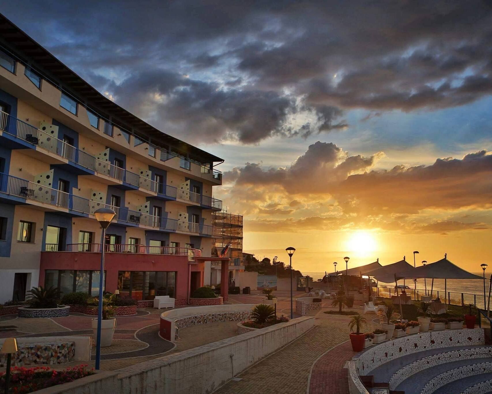 A multi-story hotel with balconies, a landscaped courtyard, and a sunset view.