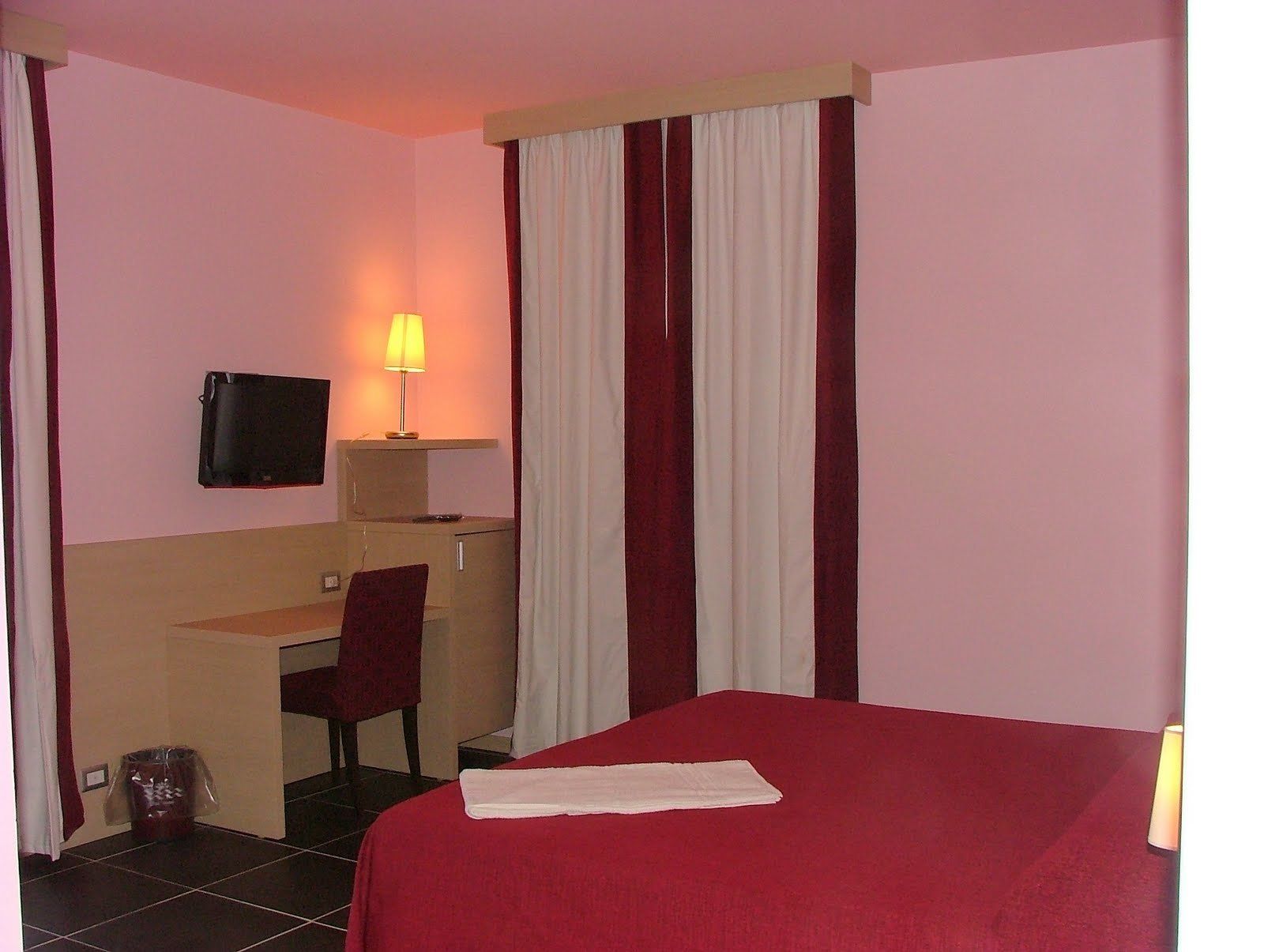 Een hotelkamer met een bed, bureau, stoel, televisie en lamp.