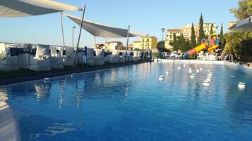 Relax by the rectangular pool surrounded by lounge chairs and a colorful water slide.