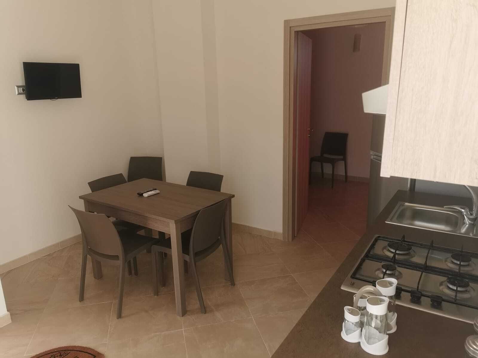 A compact kitchen with a gas stove and a dining area with a table and chairs.