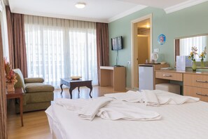 Una habitación de hotel con cama, escritorio, silla, televisor y puerta de baño.