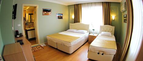 Habitación de hotel con dos camas, un escritorio y una pequeña cocina.