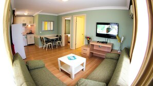Un espace de vie compact comprenant une kitchenette, un coin repas et un téléviseur.