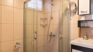 A modern bathroom with a glass-enclosed shower, a toilet, and a sink with a mirror above it.