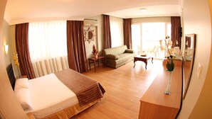 Une chambre d’hôtel avec un lit, un canapé, une petite table et un miroir.