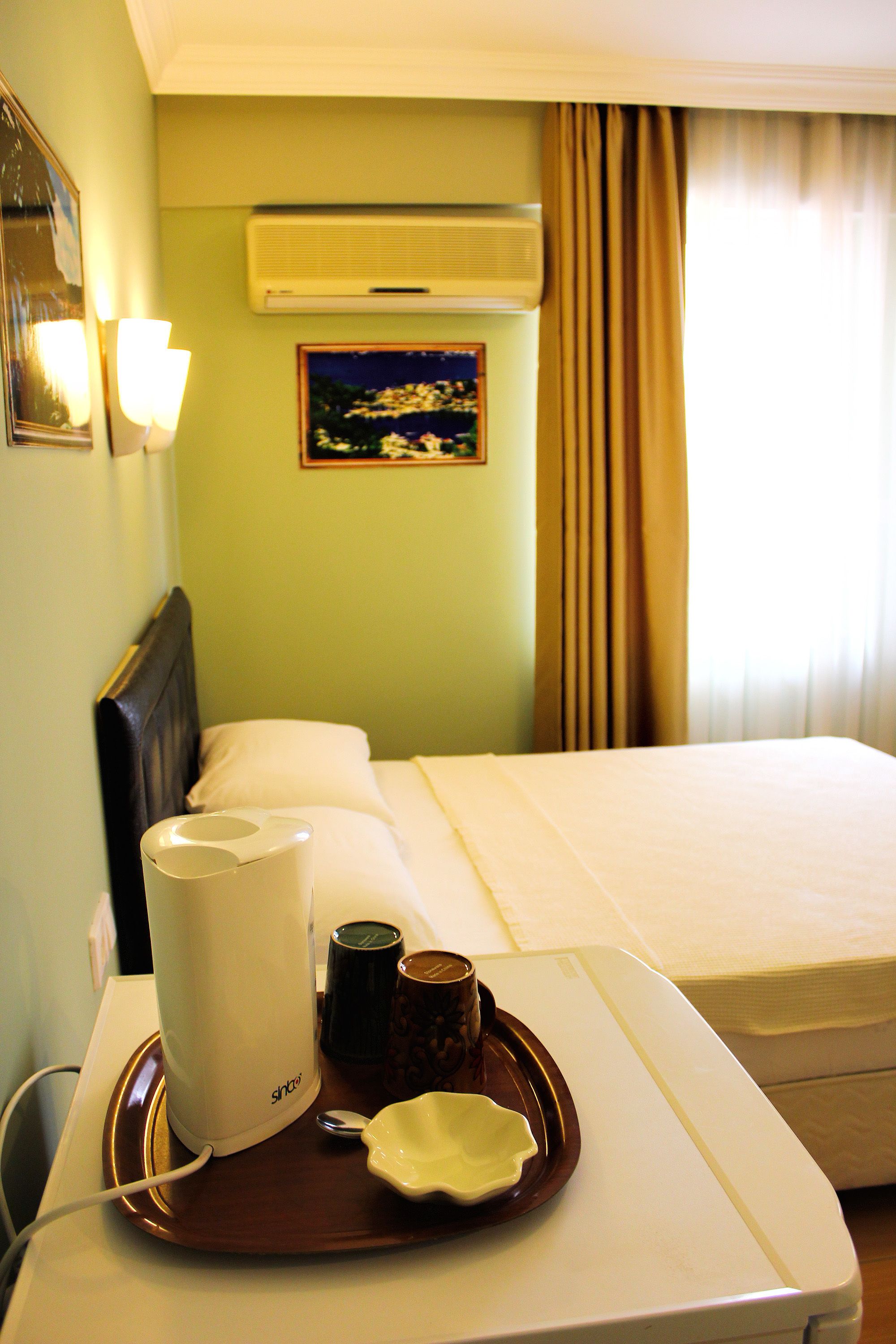 Une chambre d’hôtel avec un lit, une table de chevet sur laquelle se trouve un plateau contenant une machine à café, une tasse, ainsi qu’un salier et un poivrier.
