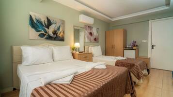 A hotel room with two beds, a wardrobe, a desk with a lamp, and a mirror.