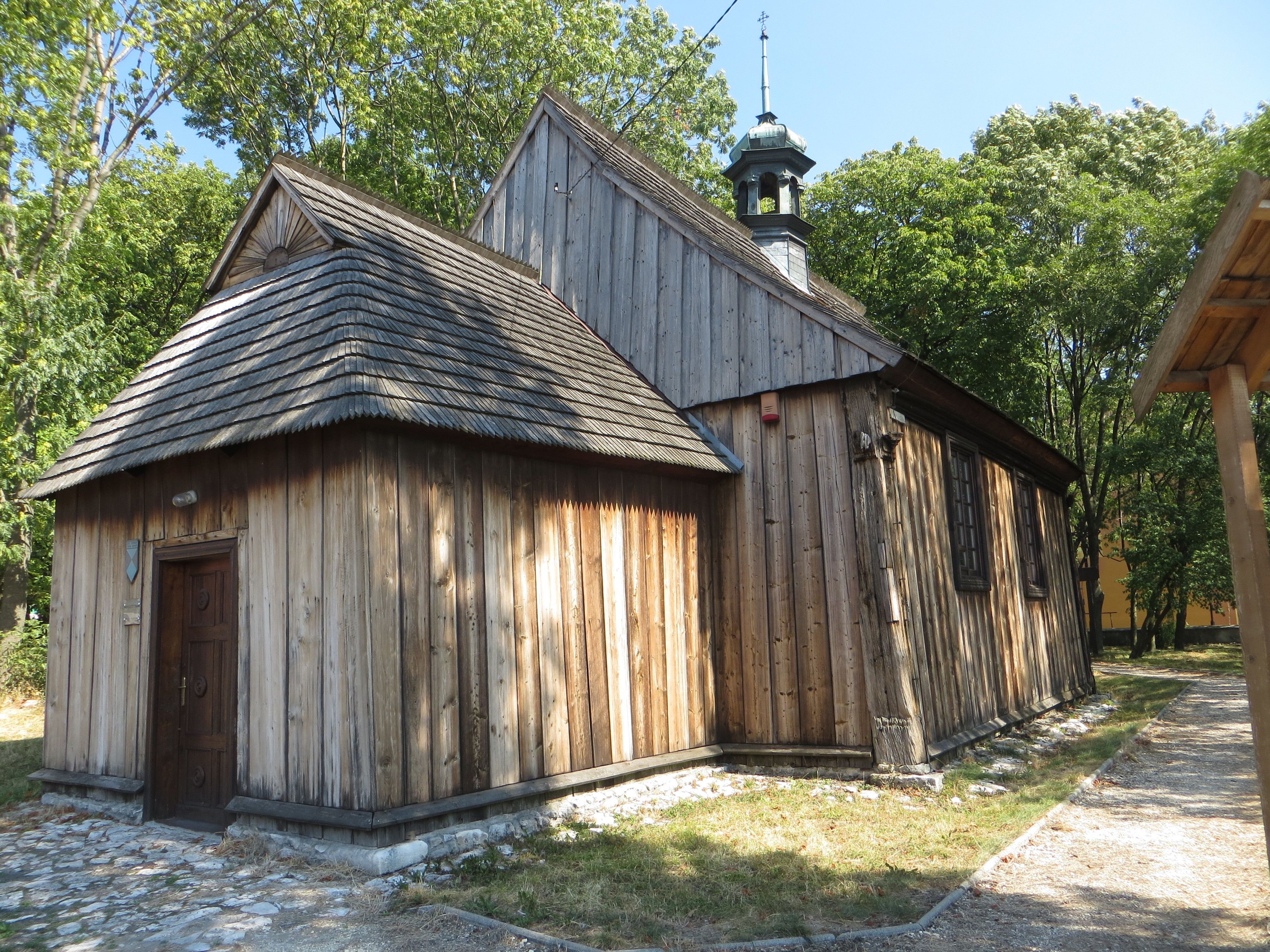 A rustic wooden building with a steeply pitched roof and a bell tower.