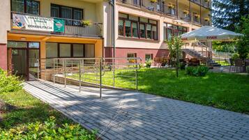 Un edificio con un cartello che riporta 'Zakład Leczniczy Gromada REHABILITACJA' e posti a sedere all'aperto con ombrelloni.