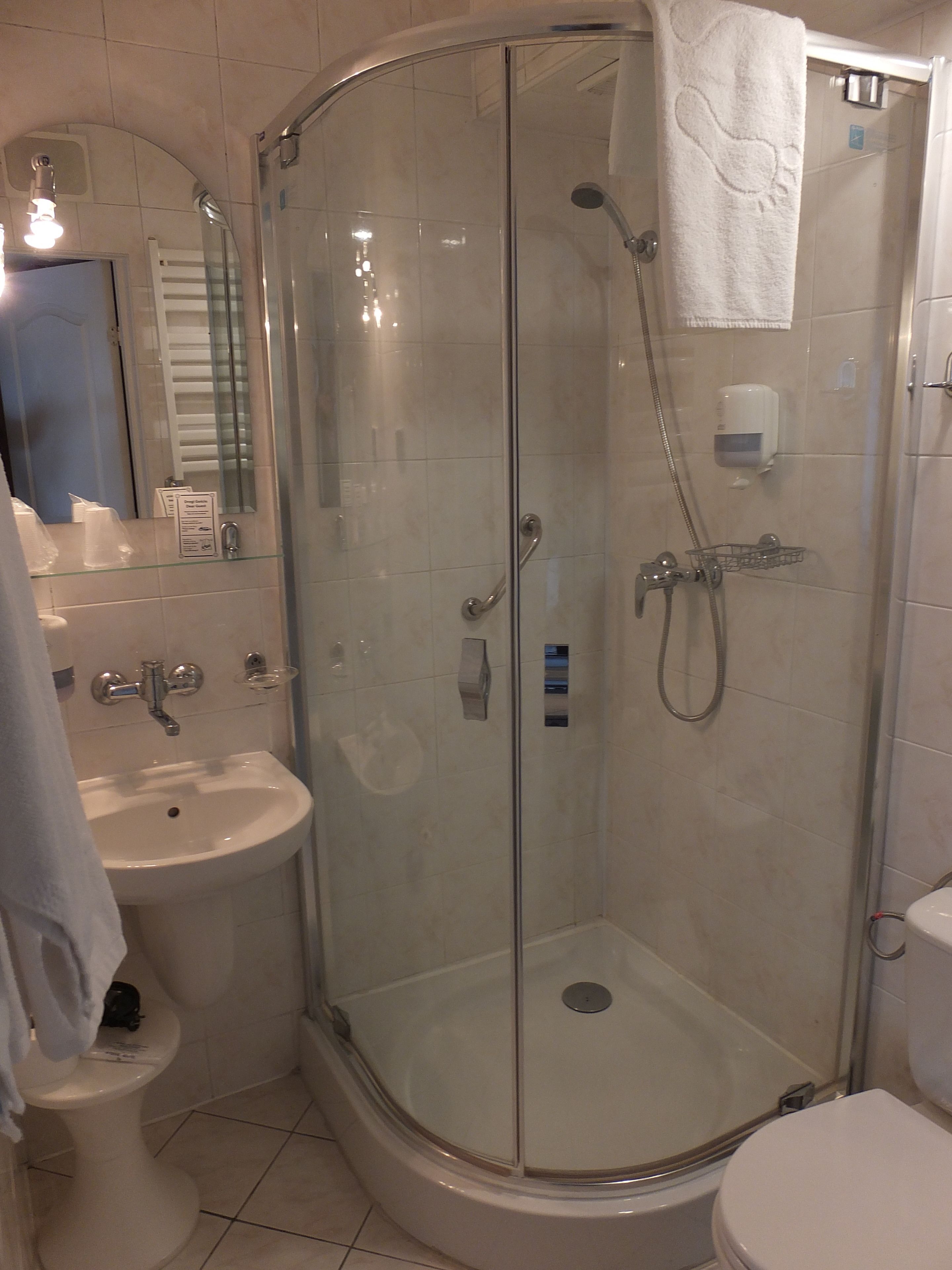Un baño con ducha de vidrio, lavamanos e inodoro.