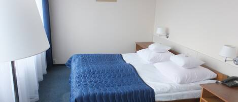 Habitación de hotel con cama, lámparas de noche, mesita de noche y un cuadro en la pared.