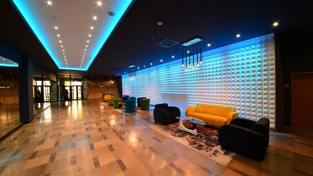 A modern lobby with a checkered floor, a reception desk, and a seating area with sofas and a coffee table. - Hotel Gromada Pila (Pila)