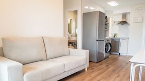Una sala de estar moderna con un sofá, una mesa de comedor y una zona de cocina con electrodomésticos.