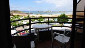 Un balcón con mesa y sillas que da a una playa y al océano.