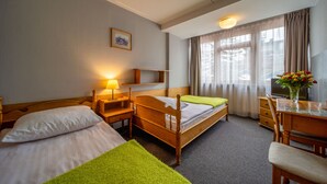 A hotel room with two single beds, a desk with a chair, a lamp, a TV, and a window with curtains. - Hotel Gromada Zakopane (Zakopane)