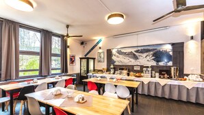 A dining area with multiple tables, chairs, and a buffet setup. - Hotel Gromada Zakopane (Zakopane)