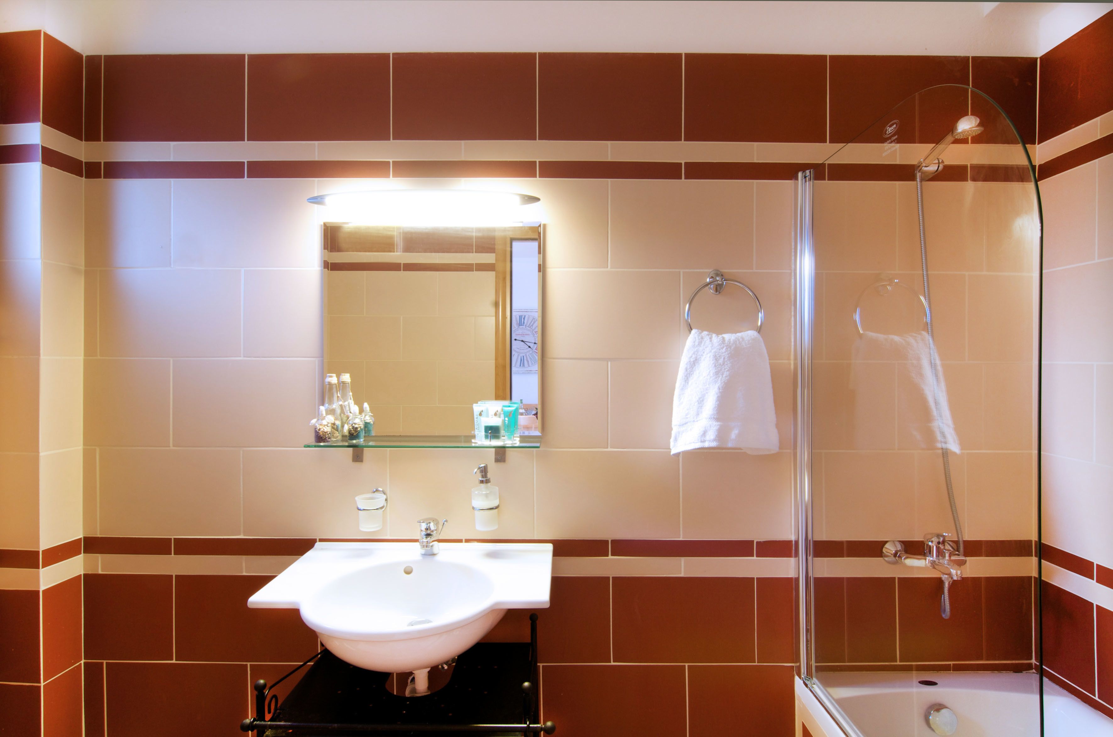 A bathroom with a sink, mirror, shower, and towel rack.