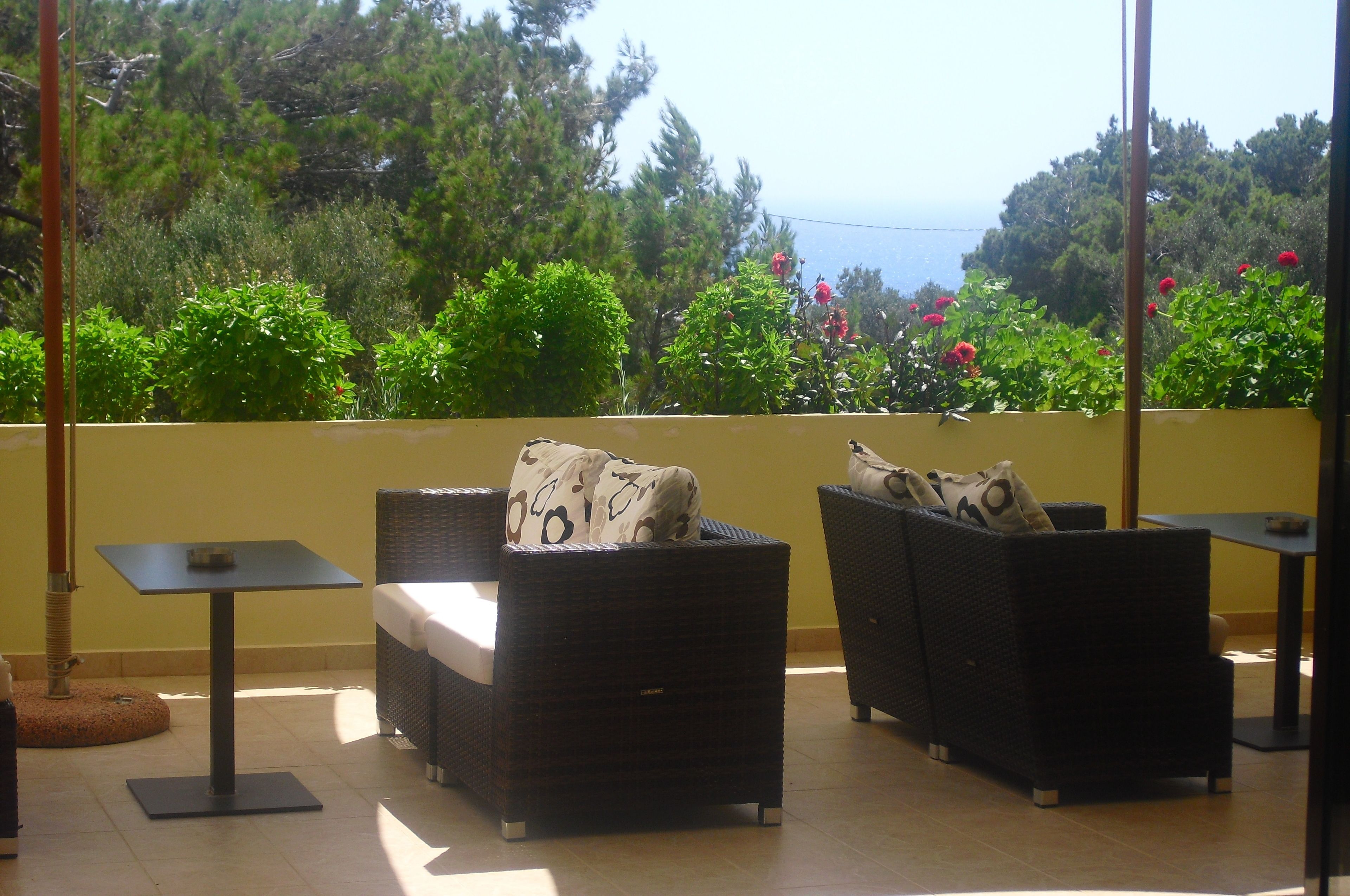 A balcony with wicker furniture and a view of the sea.