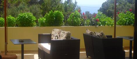 A balcony with wicker furniture and a view of the sea.