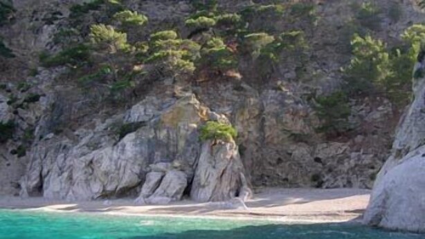 A rocky coastline with clear turquoise waters and sparse vegetation. - Miraluna Hotel (Karpathos)