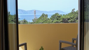 A balcony with wicker chairs, a potted plant, and a bicycle. - Miraluna Hotel (Karpathos)