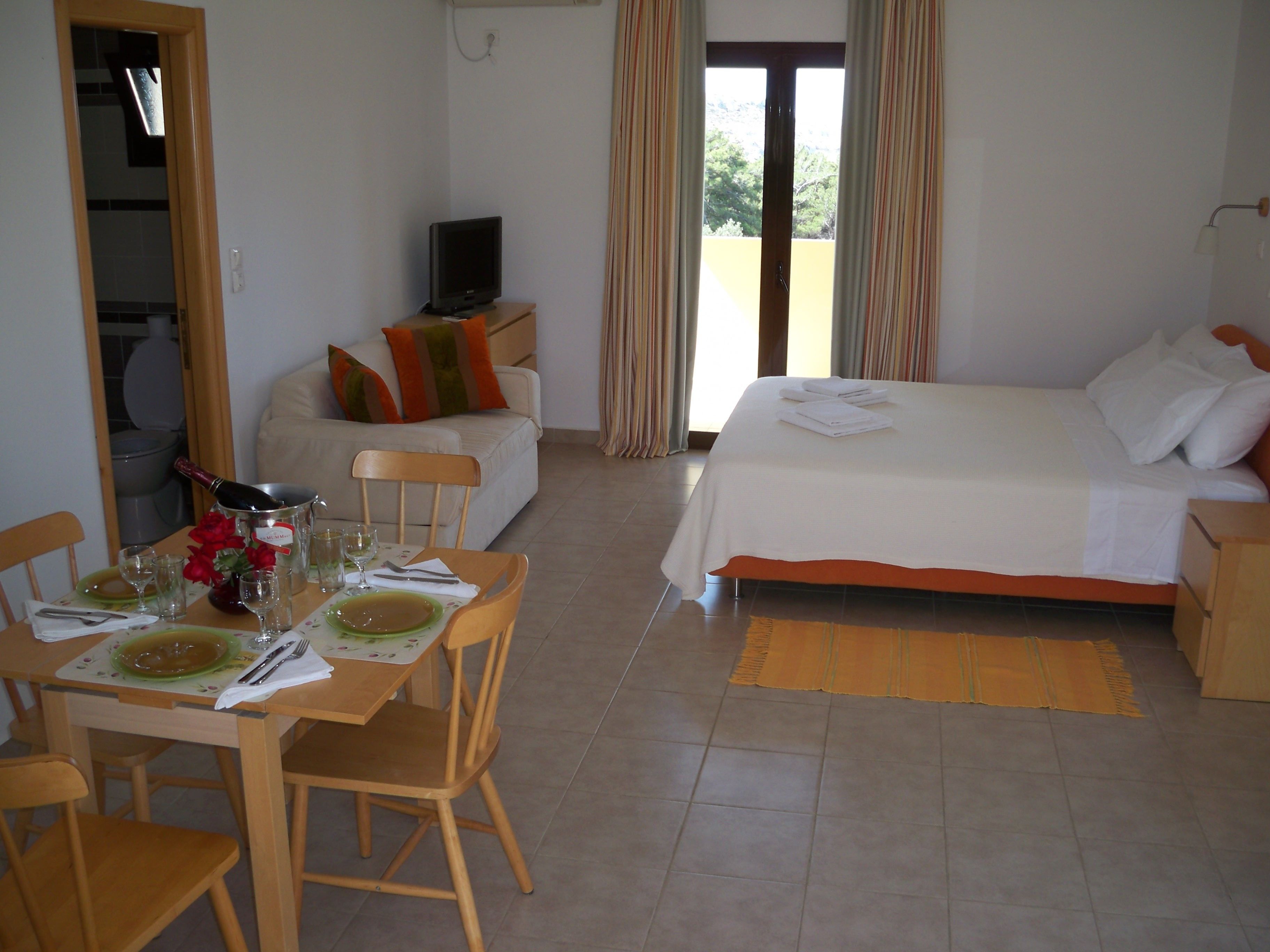 Una camera d'albergo con zona pranzo, un letto e una televisione.