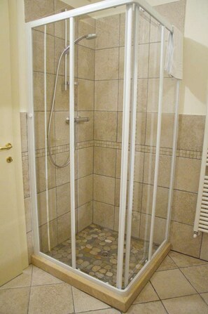 A glass-enclosed shower stall with a tiled floor and a white towel hanging on the wall. - Anfiteatro Bed and Breakfast (Lucca)