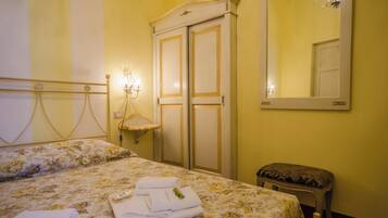 A hotel room with a bed, a wardrobe, a mirror, and a small stool.