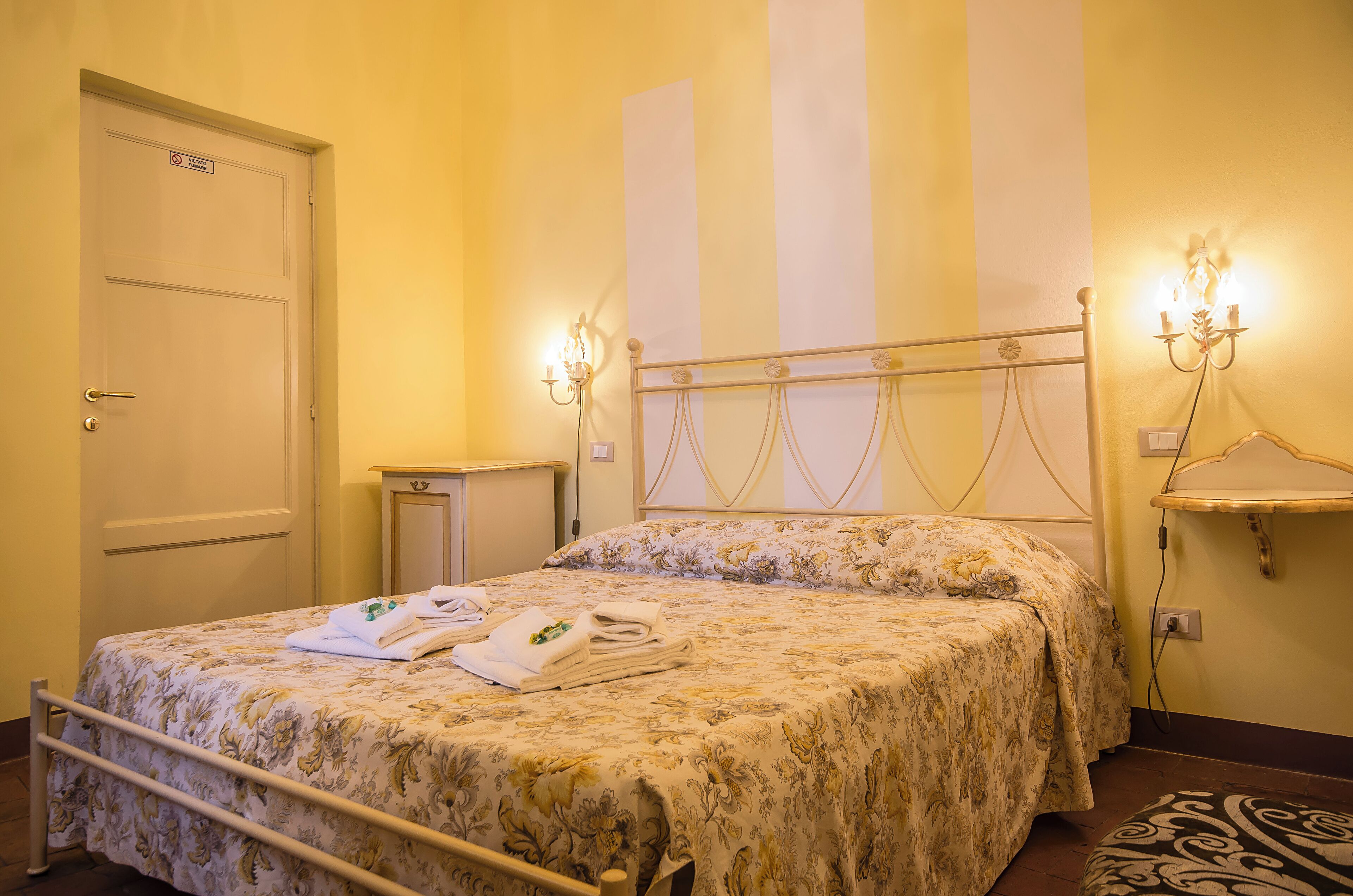 A hotel room with a bed, a nightstand, a lamp, and a door.