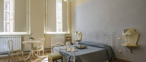 Un dormitorio con una cama, dos sillones, una mesa y una araña.