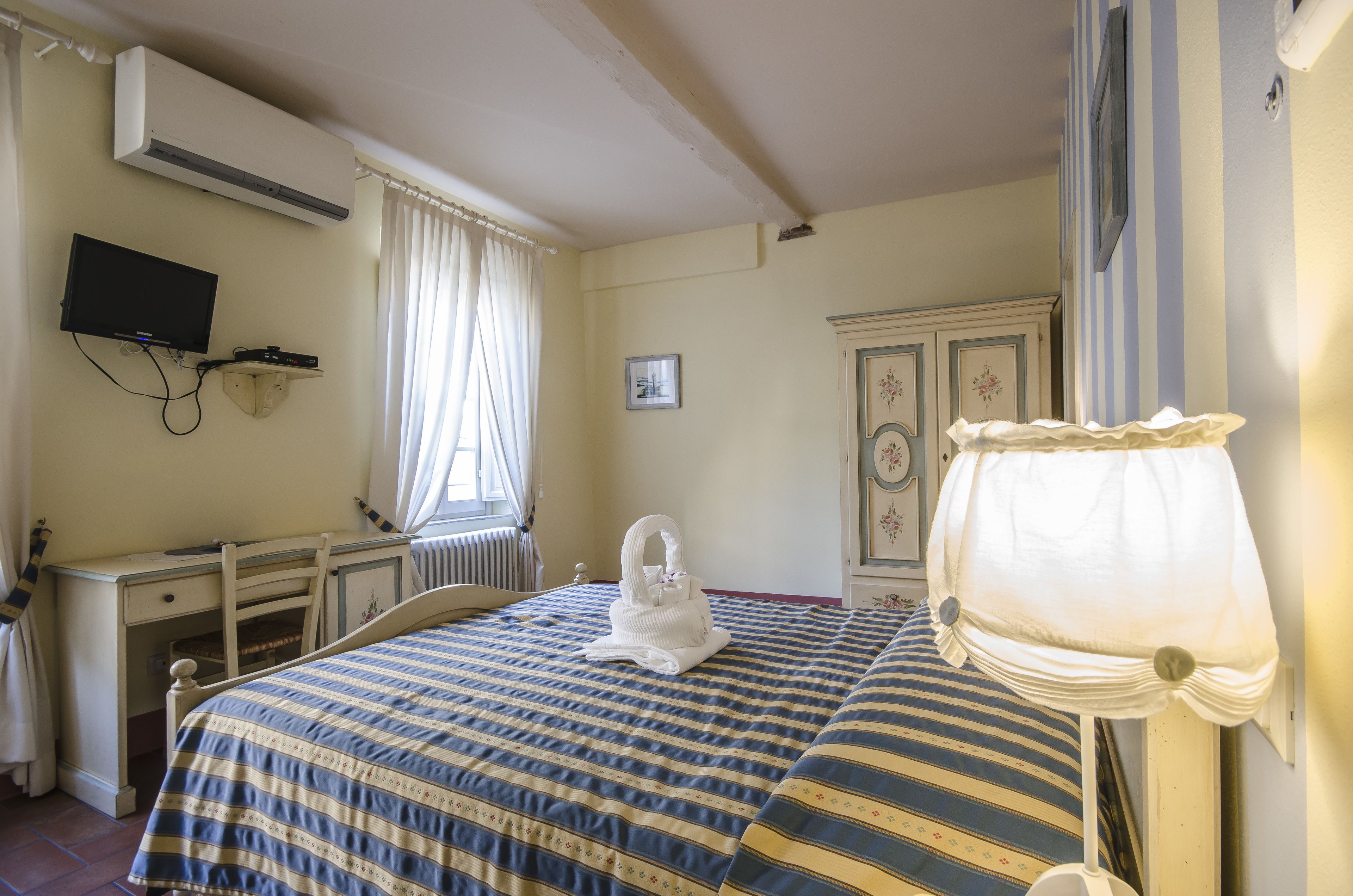 A bedroom with a bed, a desk, a television, and a radiator.