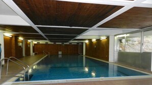 An indoor swimming pool with a wooden ceiling and tiled floor. - Hotel Sole Alto (Mezzana)