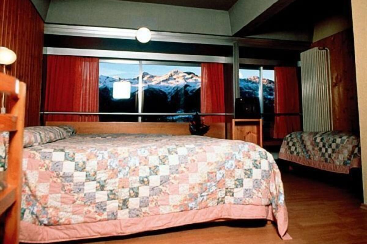 A bedroom with a large bed, a window with a mountain view, and a radiator.