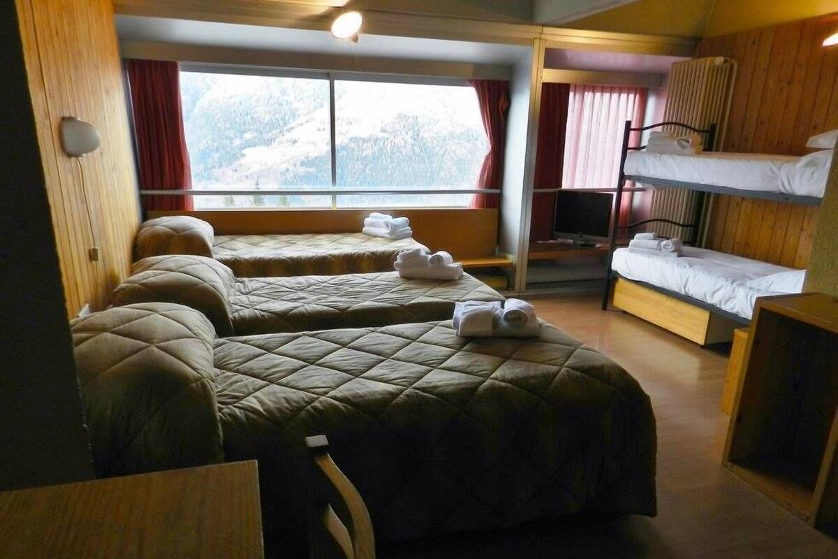 A room with two beds, a bunk bed, and a TV.