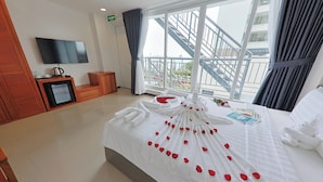 Ein Hotelzimmer mit einem großen Bett, einem Flachbildfernseher, einer Kaffeemaschine und Blick auf einen Balkon mit Treppe.