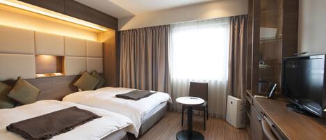 A hotel room with two beds, a small table, a TV, and a minibar.