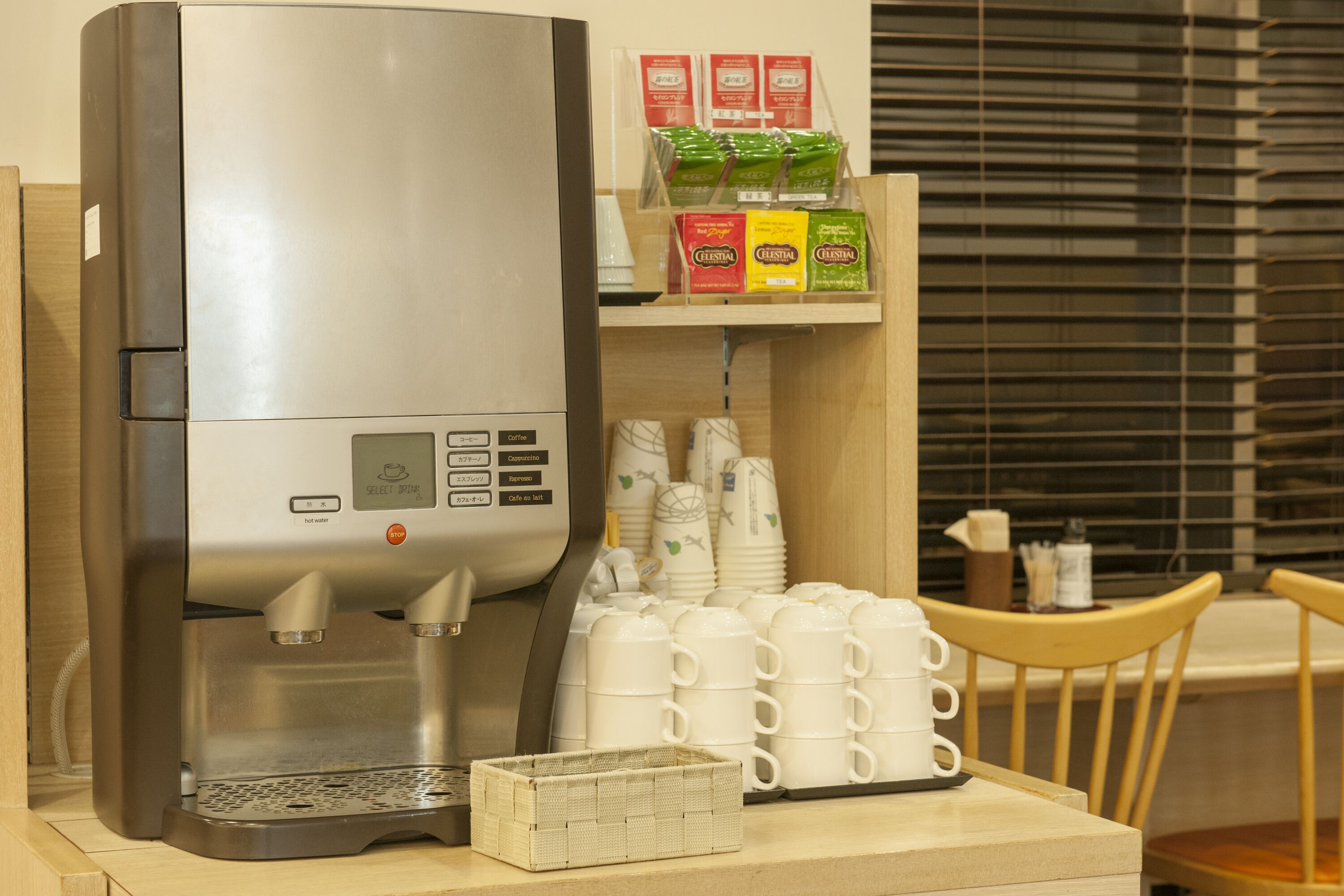 Una cafetera con diversas opciones de café, una pila de vasos desechables y una presentación de cápsulas de café.