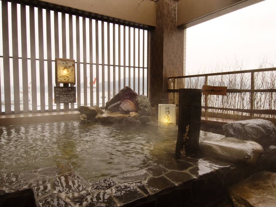 A hot spring bath with stone seating and a wooden fence.
