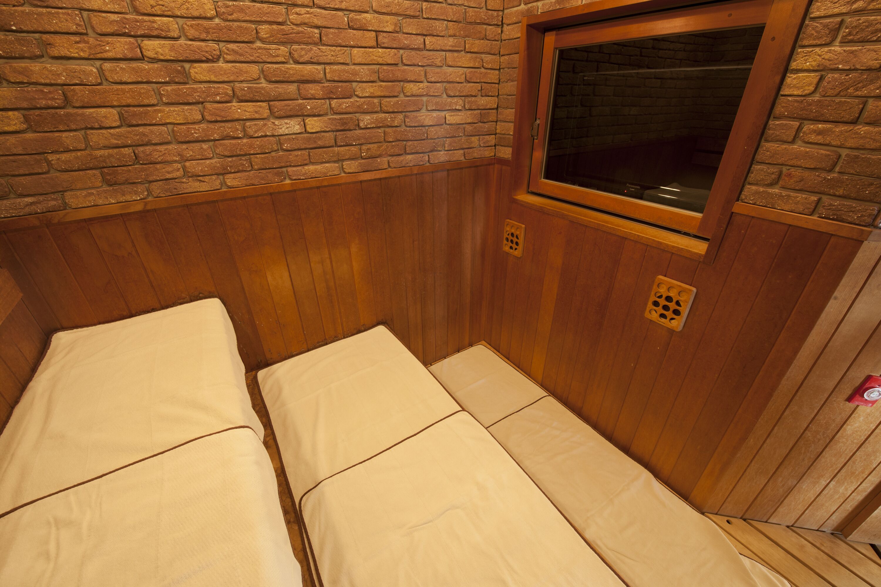 A small, wooden room with two beds and a window.