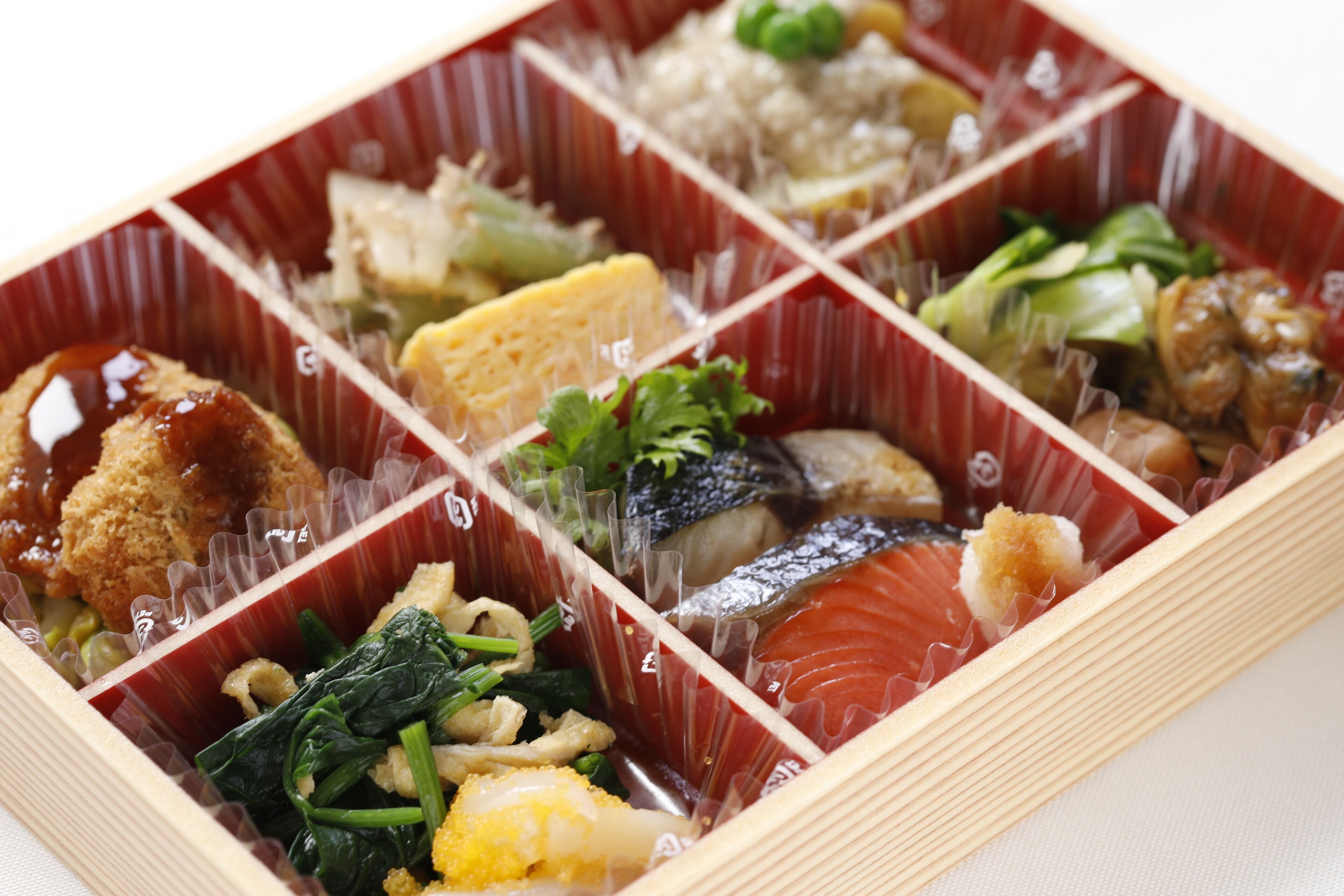 Une boîte à bento contenant divers aliments, notamment du poisson, des légumes et du riz.