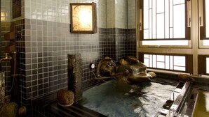 A traditional Japanese onsen with tiled walls, a wooden bench, and a stone basin.