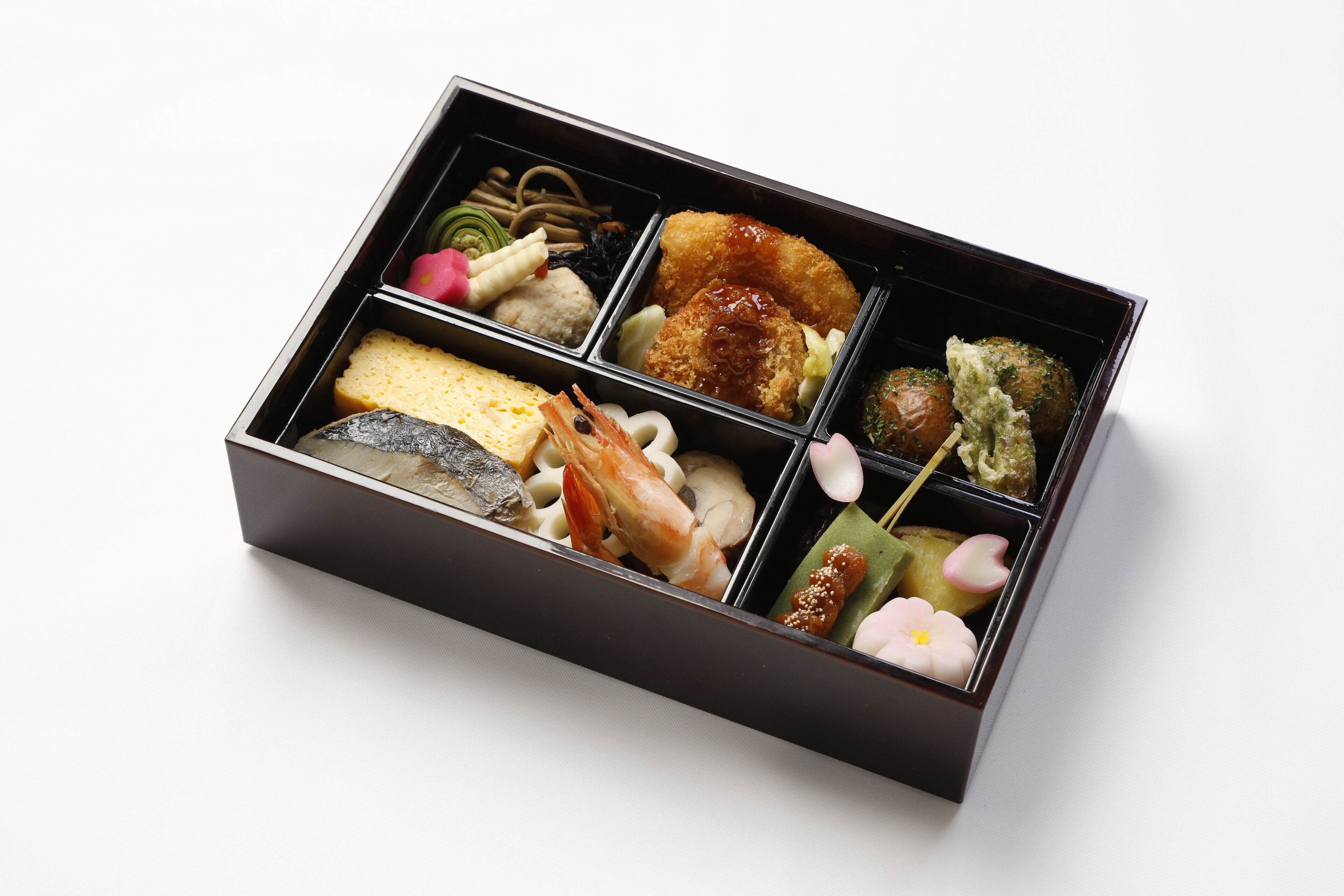 A bento box with various food items including fish, vegetables, and a piece of bread.