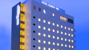 A modern hotel building with a sign reading "HOTEL DORMY INN" at the top.