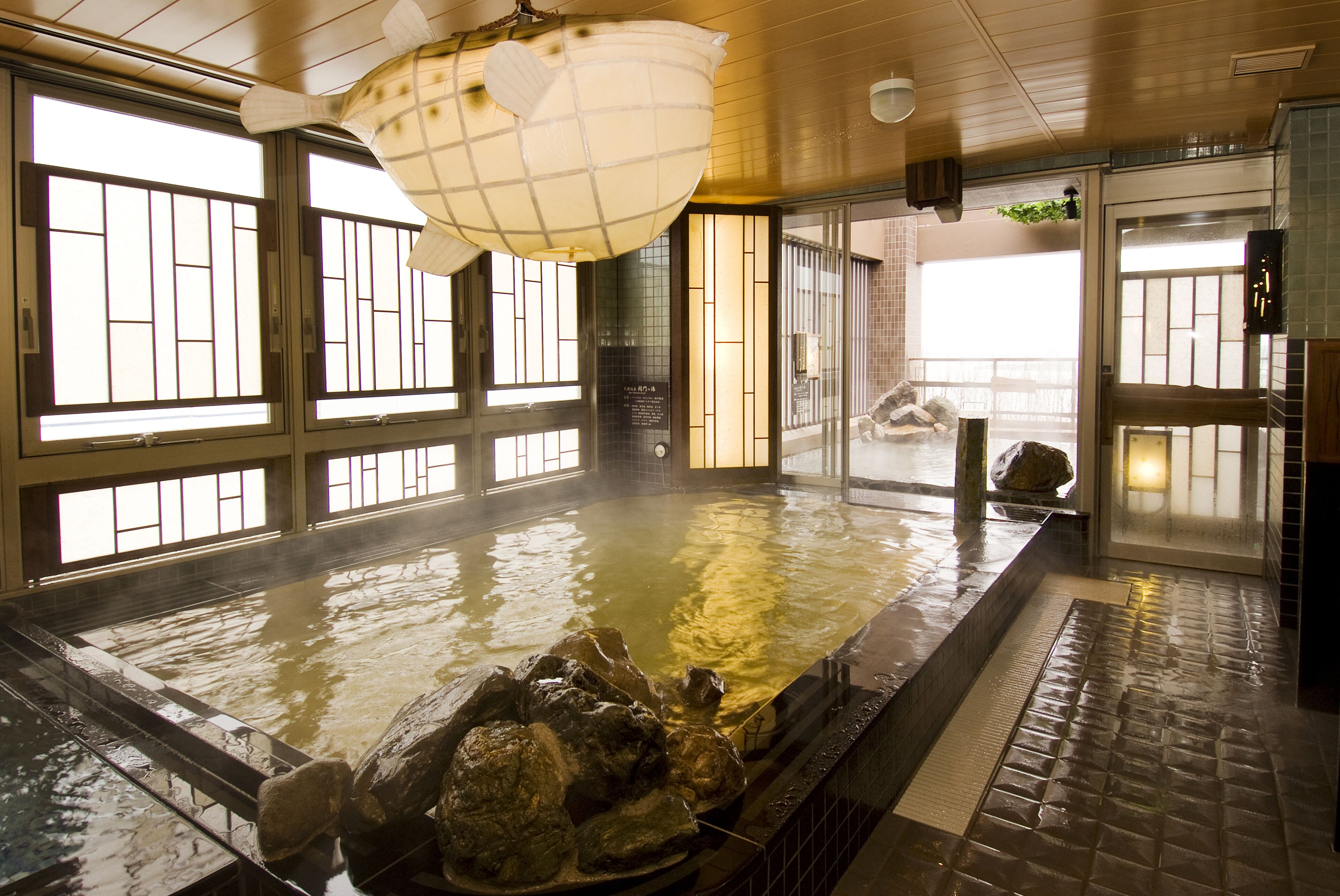 Ein traditionelles japanisches Onsen mit einem großen Thermalbad, Holzböden und Schiebetüren.