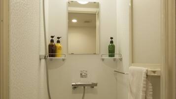 A small, enclosed shower area with a handheld showerhead, a mirror, and two shelves with toiletries.