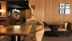 Ein Restaurant mit Holztischen, Pendelleuchten und gerahmten Bildern an der Wand.