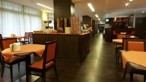 Un restaurante con mesas y sillas de madera, una zona de bar y una pantalla de televisión.